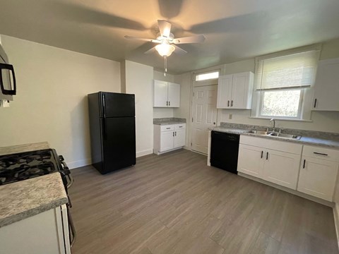 A kitchen with a black fridge and white cabinets.at North Pointe Commons Apts, Pittsburgh, 15229